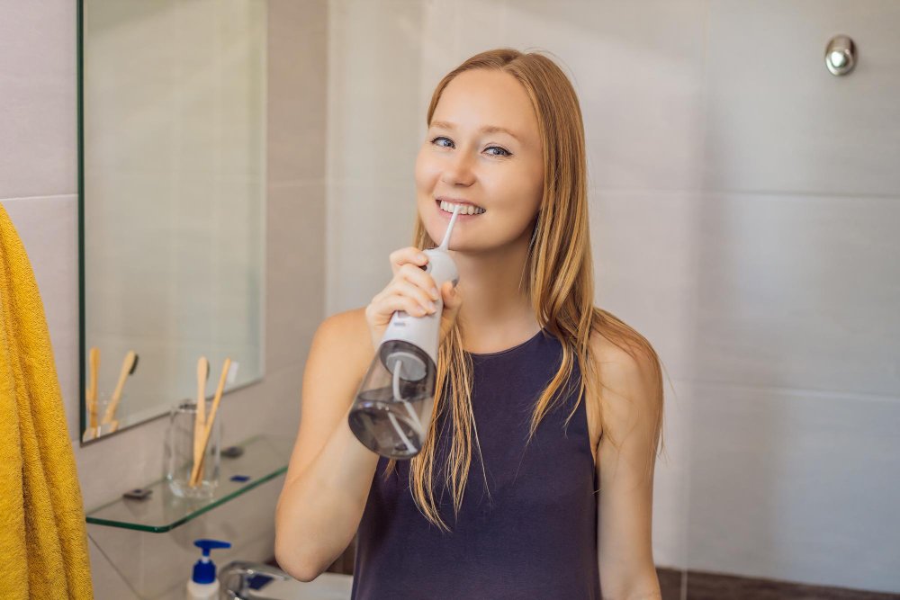 Girl using water flosser on her teeth for effective oral care and plaque removal.